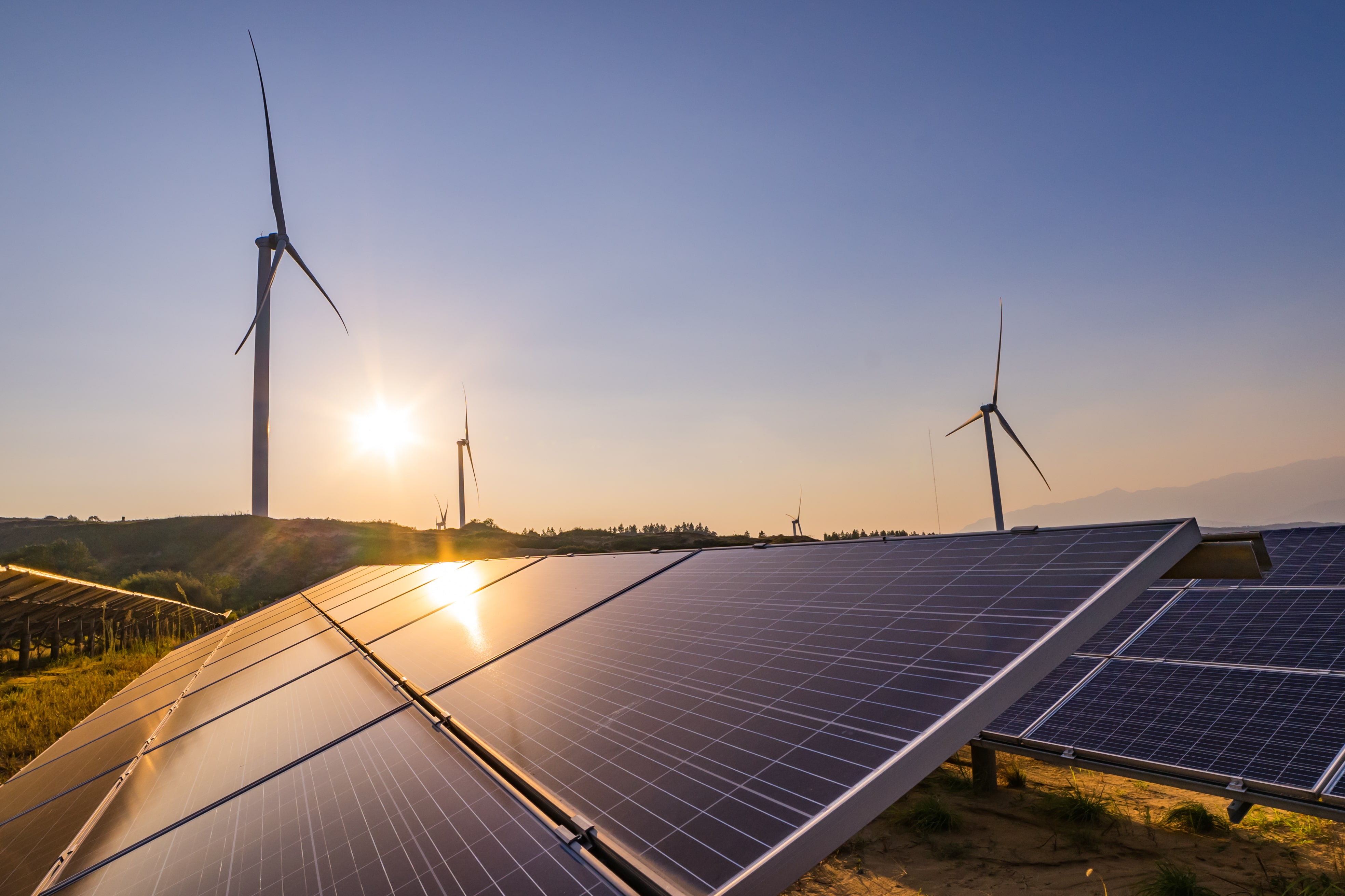 Solar Panels in a field with windmills in the background